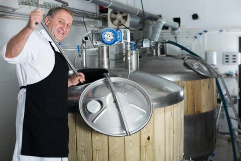 Brewer is controls the brewing process near reservoir with beer Stock Photos