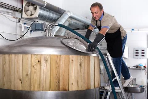 Brewer is controls the brewing process near reservoir with beer Stock Photos