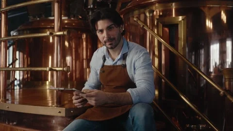 Brewer man wearing an apron is studying a clipboard in a brewery setting Video stock 317678656