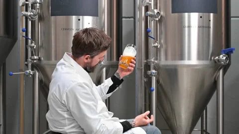 Brewer wearing white coat controlling process of beer fermentation while working Stock Footage 192546400