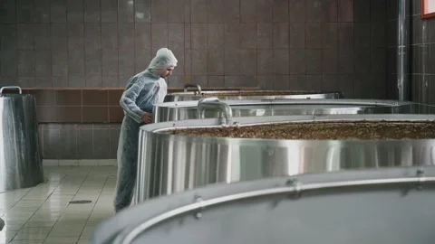 A brewery employee controls the process of brewing beer in a huge steel tanks in Vidéo 237198614