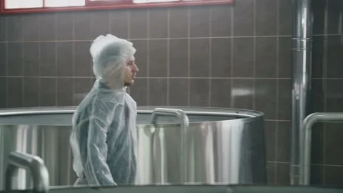 A brewery employee controls the process of brewing beer in a huge steel tanks in Vidéo 237198643