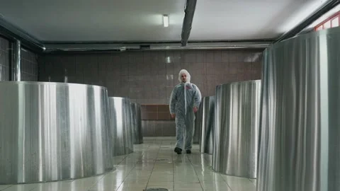 A brewery employee controls the process of brewing beer in a huge steel tanks in Vidéo 237198696