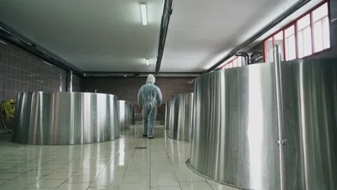 A brewery employee controls the process of brewing beer in a huge steel tanks in Vidéo 237198732