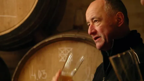 Brewery Owner Gesturing and Talking During Lambic Beer Tasting in Cellar Видео 347059606
