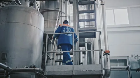 Brewery worker walking on an industrial platform Stock Footage 337411026