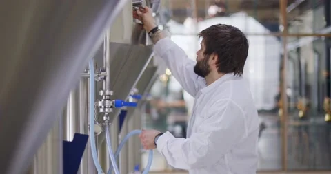 Brewery worker in work process. Man dressed in lab coat at brewery factory near Video stock 148230889