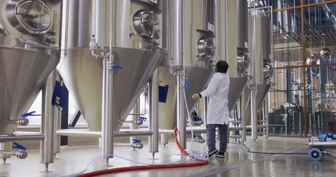 Brewery worker in work process. Man dressed in lab coat at brewery factory near Stock-Footage 148230982