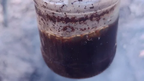 Brewing coffee in a glass jar over a campfire lifehack Stock Footage 333844806
