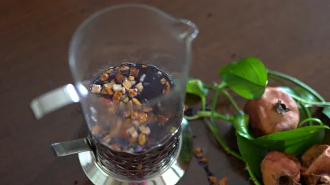 Brewing herbal tea in transparent tea pot, pieces of dried pomegranate fruit Stock Footage 130233581