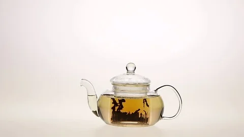 Brewing leaf tea in a transparent glass teapot. White background Stock Footage 73855580