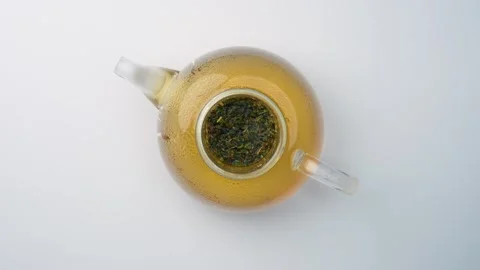 Brewing melissa herbal tea in open glass teapot. Top view, transparent teapot Stock Footage 342976489