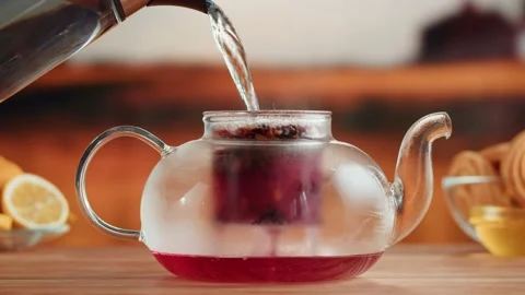 Brewing red tea close-up. Pouring hot water into teapot with fruit tea on a Stock Footage 192398606