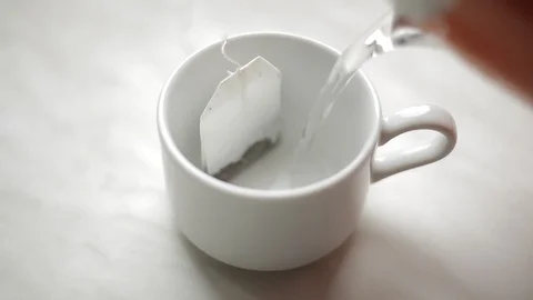 Brewing a tea bag with boiling water in a white mug Stock Footage 128243612