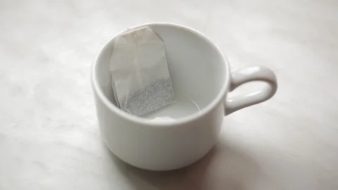 Brewing a tea bag with boiling water in a white mug Stock Footage 128243748