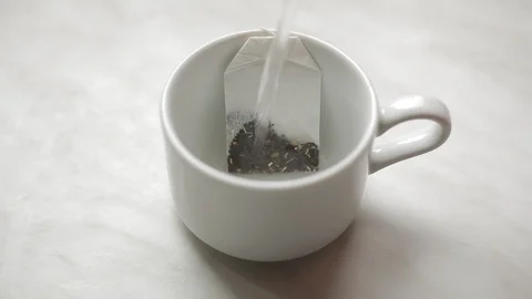 Brewing a tea bag with boiling water in a white mug Stock Footage 128243838