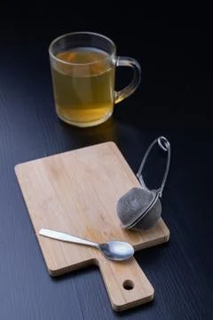 Brewing tea on a black table. Mug with a warm drink. Stock Photos