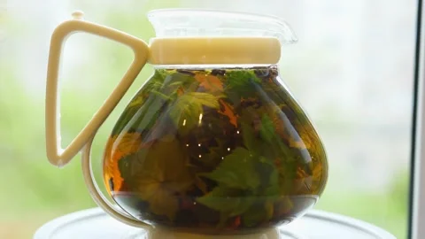 Brewing tea with leaves of currant, lemon balm, mint, raspberry in a glass Stock Footage 131453803