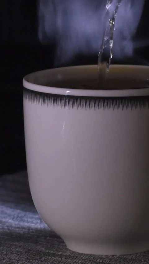 Brewing tea in a tea bag in a white cup, close-up. dark background, steam Stock Footage 310495207