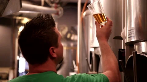 Brewmaster checks for clarity and taste testing the brew at brewery 1293 Stock Footage