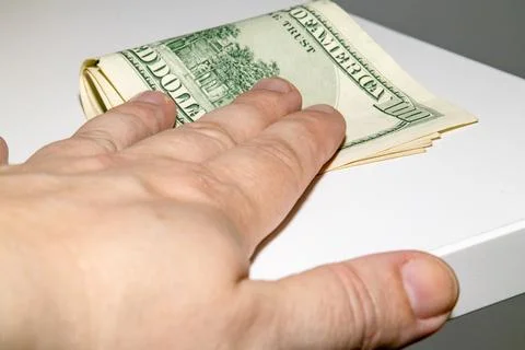 Bribery concept. A hand covers a stack of US dollar bills Stock-Fotos