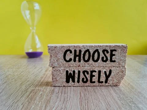Brick blocks with CHOOSE WISELY text on a beautiful yellow background Stock Photos