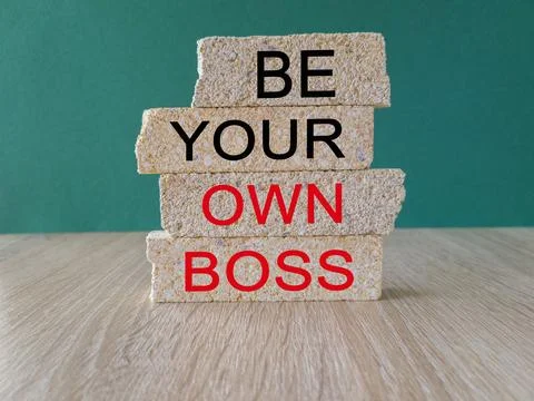 Brick blocks form the words 'be your own boss' on beautiful green background. Stock Photos