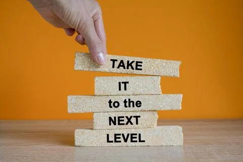Brick blocks with the message take it to the next level. Businessman hand. Stock Photos
