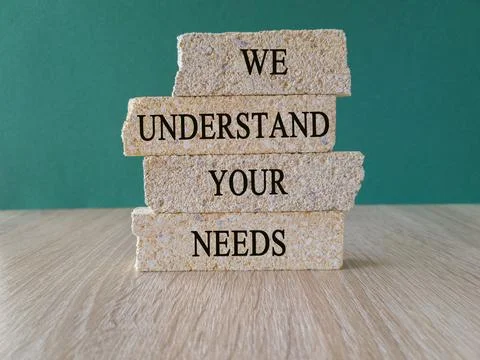 Brick blocks with WE UNDERSTAND YOUR NEEDS text on beautiful green background Stock Photos