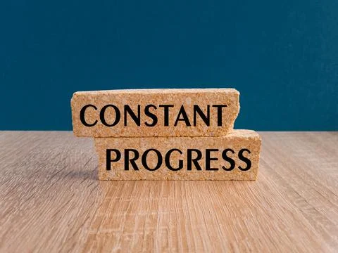 Brick blocks with words Constant Progress. Beautiful wooden table Stock Photos