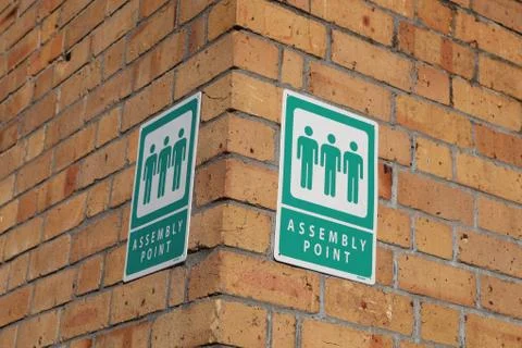 Brick building with Assembly point sign. Stock Photos