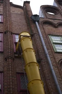 Brick Building with Bright Yellow Pipe for Construction Waste Disposal Stock Photos