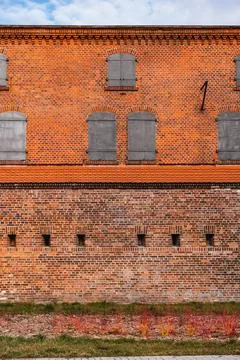 Brick building with closed windows over medieval brickwall Stock Photos