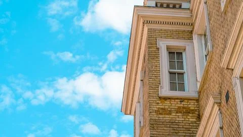 Brick building corner with window against blue sky and clouds Stock Photos