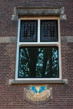 A brick building facade with a decorative window featuring stained glass. Fotos de archivo