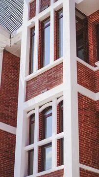 Brick building facade with white architectural trim and tall windows shown Stock Photos