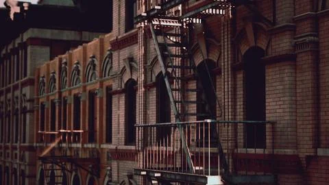 A brick building with a fire escape next to it Ilustración de archivo