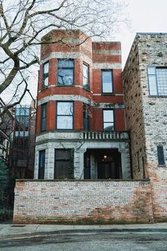 A brick building with multiple stories has large windows and a balcony. Nearb Fotos Stock