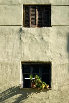Brick building with multiple windows, adorned with ornamental pots and blooming Fotos de archivo