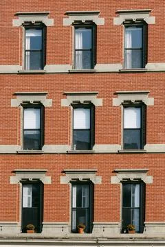 Brick building with multiple windows and flower pots in a city street during the Stock Photos