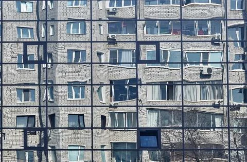 The brick building is reflected in the windows of the modern new glass facade Stock Photos