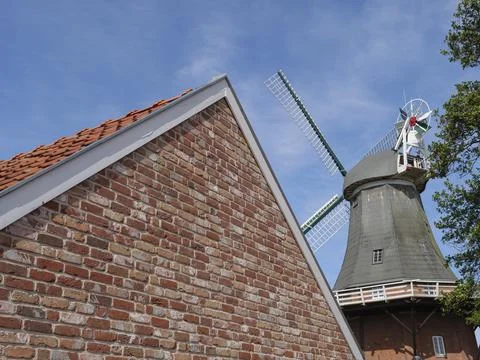 Brick building with the top of a windmill in the background under a blue sky, Fotos de archivo