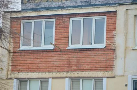 A brick building with two windows on the side.  Stock Photos