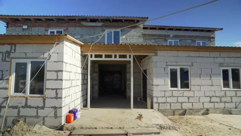 A brick building under construction, against a blue sky background. Building and Stock Footage 171364604