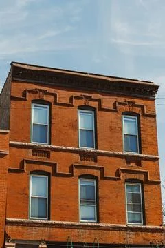 Brick building with windows and decorative elements in a city setting under.. Stock Photos