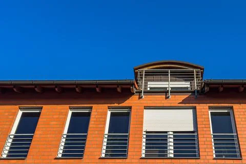 Brick building with windows under clear blue sky in urban setting Stock Photos