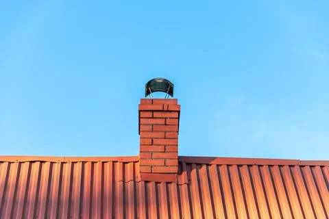 Brick chimney made of clinker bricks with a chimney cowl. Stock Photos