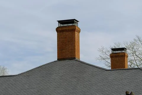 Brick chimney stack on modern contemporary house roof top Stock Photos