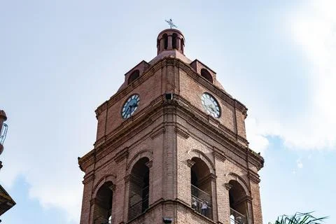 Brick clock tower with a cross and arches under a clear sky Stock Photos