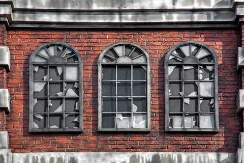 Brick facade of an abandoned building with broken windows. Stock Photos